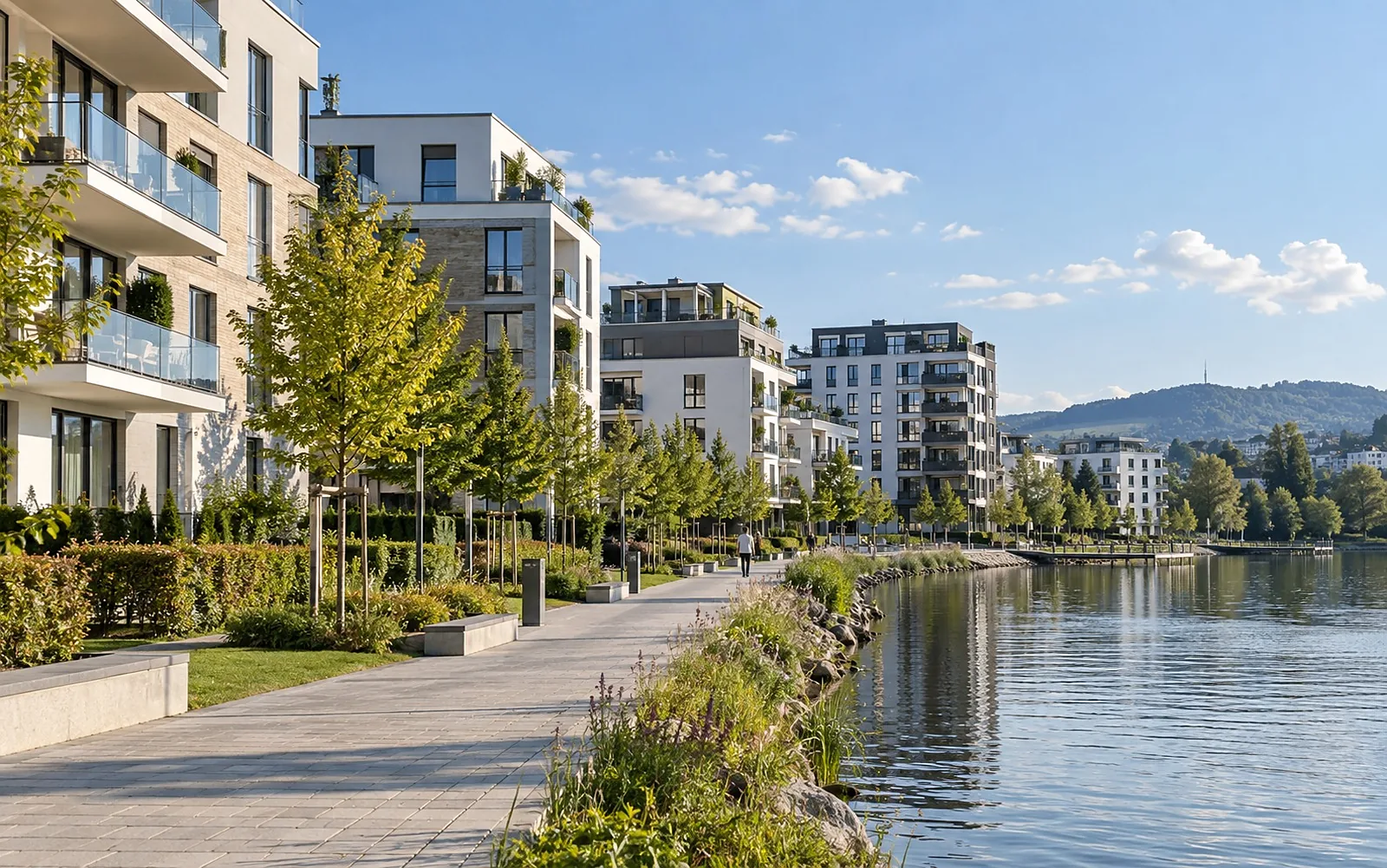Neue Stadthäuser und Mehrfamilienhäuser an einem Seeufer mit Promenade